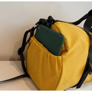 Detailweergave van de elastische zijzak van een gele sporttas waarin een groene tabletbehuizing zit.