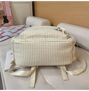 Vue détaillée du fond d'un sac à dos à carreaux crème avec de larges bretelles
