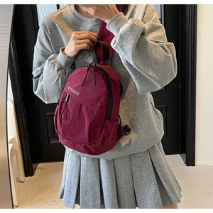 Dunkelrote Streetstyle-Nylon-Brusttasche, getragen von einem Modell im Innenraum