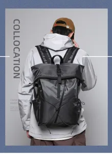 Back view of a male model wearing a grey roll-top commuter backpack with buckle closure