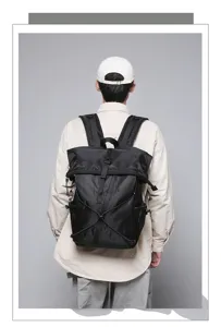 Detailed rear view of a black roll-top commuter backpack worn by a model in a studio