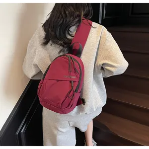 Rückansicht einer burgunderroten Nylon-Umhängetasche auf einem grauen Sweatshirt