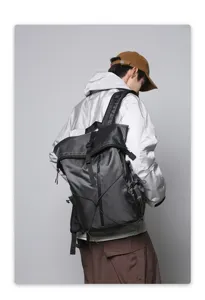 Detail view of black roll-top backpack worn by a model in urban techwear style