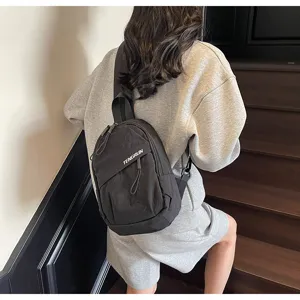 Detailansicht eines schwarzen Nylon-Brustbeutels im Streetstyle an einem Model auf einer Treppe