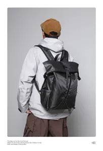 Rear view of black roll-top backpack on model for daily commuting