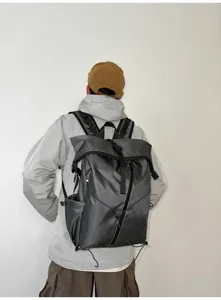 Rear view of a men's grey roll-top commuter backpack with buckle closure and cords
