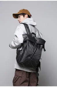Detailed side view of a black roll-top backpack worn by a male model for business commuting