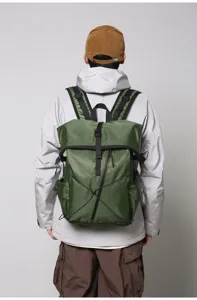 Rear view of a man wearing a large green roll-top commuter backpack with buckle detail