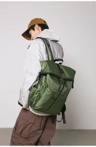 Back view of a man carrying a large olive green roll-top backpack for daily commute