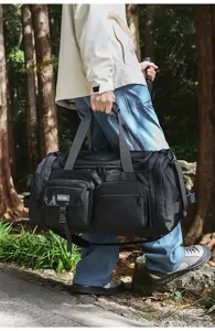 Side view of a large black multi-pocket duffel bag carried during an outdoor hiking trip.