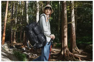 Large black fitness travel duffle bag with multi-pockets shown in outdoor hiking scene