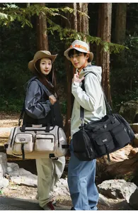Models in forest setting carrying beige and black large multi-pocket fitness duffle bags
