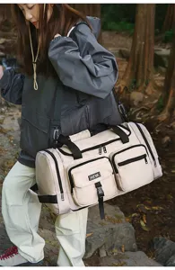 Outdoor lifestyle view of a large beige fitness duffel bag with multiple front pockets