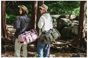 Models showcasing pink and olive green large capacity travel bags in a forest outdoor setting