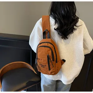 Rückansicht einer Person mit einer braunen, lässigen Canvas-Umhängetasche im Moto-Stil.