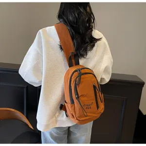 Detailansicht einer orangefarbenen Umhängetasche aus Nylon mit Reißverschlussdetails