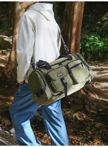 Asian male model carrying a large green multi-pocket sports gym bag in a forest setting