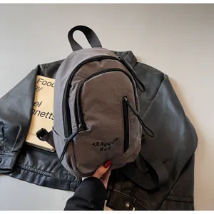Nahaufnahme einer grauen Nylon-Crossbody-Tasche im Workwear-Stil mit Reißverschlüssen
