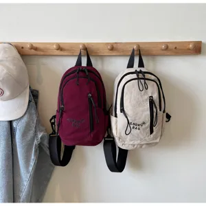 Detailansicht kleiner Umhängetaschen in Burgund und Beige an einem Holzregal aufgehängt.