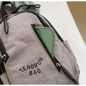 Detailaufnahme einer grauen Umhängetasche aus Nylon mit einer Handytasche mit Reißverschluss.