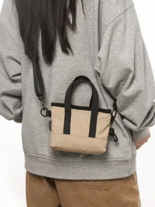 Stylish mini khaki crossbody bag with black contrast straps worn by a female model