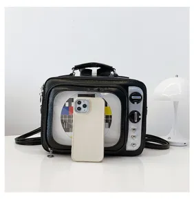 Retro TV-shaped black PU leather handbag shown with a phone for size comparison.
