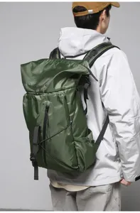 Rear view of a male model wearing a large green roll-top business commuter backpack