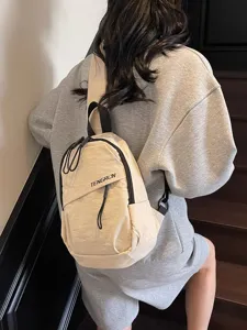 Minimalistische neutrale beige Crossbody-Brusttasche im Streetstyle, getragen von Model auf Treppe