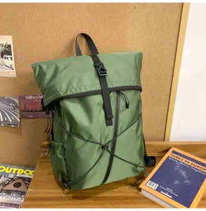 Detailed view of a green roll-top backpack featuring a black strap buckle and elastic cords