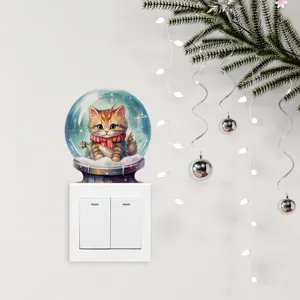 Detalle de una pegatina de pared de gato en bola de nieve de Navidad sobre un interruptor blanco