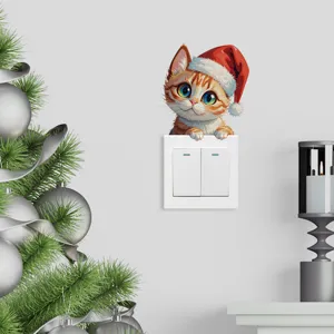 Primer plano de una pegatina de gato navideño asomando por un interruptor de luz blanco