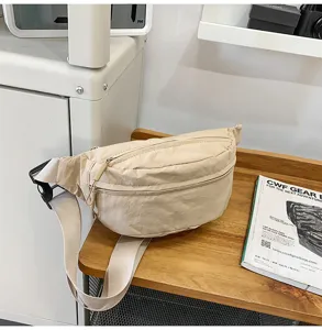 Detailansicht einer minimalistischen beigen Nylon-Gürteltasche auf einer Holzoberfläche