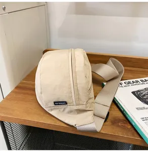 Nahaufnahme einer minimalistischen beigen Nylon-Umhängetasche auf einem Holzregal