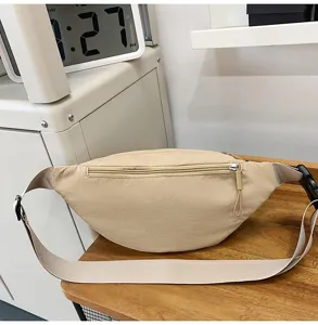 Detailansicht einer minimalistischen beigen Sport-Bauchtasche auf einem Holztisch.
