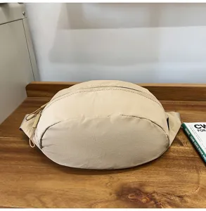 Detailansicht einer minimalistischen beigen Nylon-Sportgürteltasche auf einem Holztisch