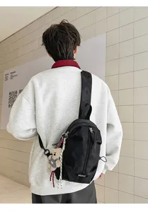Black casual outdoor sling bag with a cute bear pendant shown in a lifestyle setting