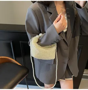 Elegante gewebte Perlen-Abendtasche mit großem Perlengriff an der Schulter des Models.