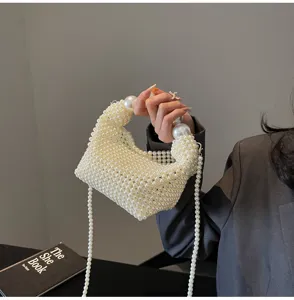 Detailansicht einer Hand, die eine weiße gewebte Perlen-Abendtasche hält.