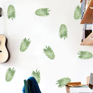 Close-up detail view of green fern leaf wall stickers on a white minimalist bedroom wall
