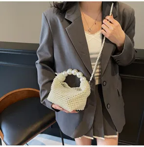 Elegante weiß gewebte Perlen-Abendtasche mit großem Griff und Kettenriemen am Modell