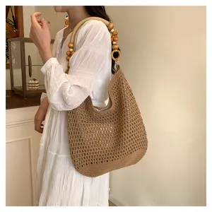 Vue détaillée d'un sac cabas au crochet marron tissé à la main avec anse en bois.