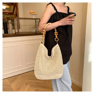 Gros plan sur un sac cabas au crochet fait main avec une poignée décorative en perles de bois.