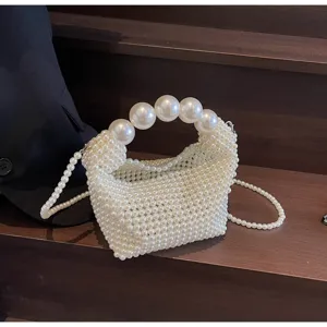 Nahaufnahme einer eleganten weißen Perlen-Abendtasche mit großem Griff und Perlen-Trageriemen