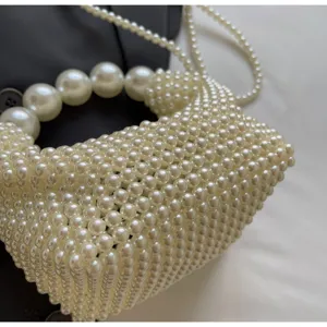Detailansicht einer weiß handgewebten Perlen-Abendtasche mit großem Perlengriff und Kette.