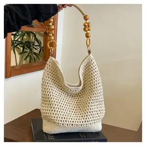 Sac fourre-tout beige en maille ajourée avec une bandoulière en perles de bois.