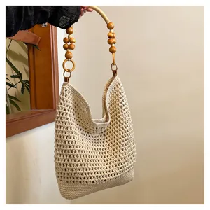 Gros plan d'un sac cabas en tricot ajouré fait main avec une poignée en perles de bois