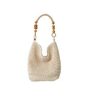 Gros plan d'un sac cabas en tricot ajouré tissé main avec poignée en perles de bois.