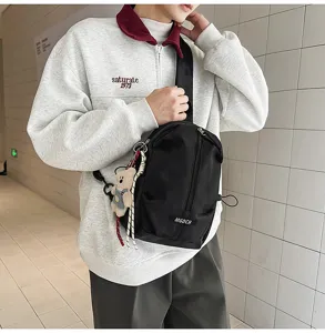 Male model wearing a black minimalist chest bag with a cute bear keychain in a lifestyle setting