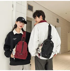 Detail view of unisex casual sling bags in red and black colors worn by models.