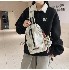 Detailed view of tie-dye canvas sling bag featuring a cute bear keychain and MGDCH label